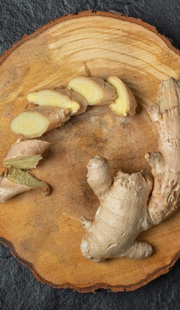 Sliced ginger roots on wooden piece Sliced ginger roots on wooden piece. High quality photo